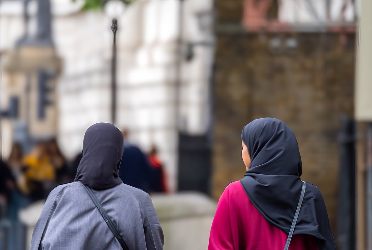 Two friends in hijab walking together through a city