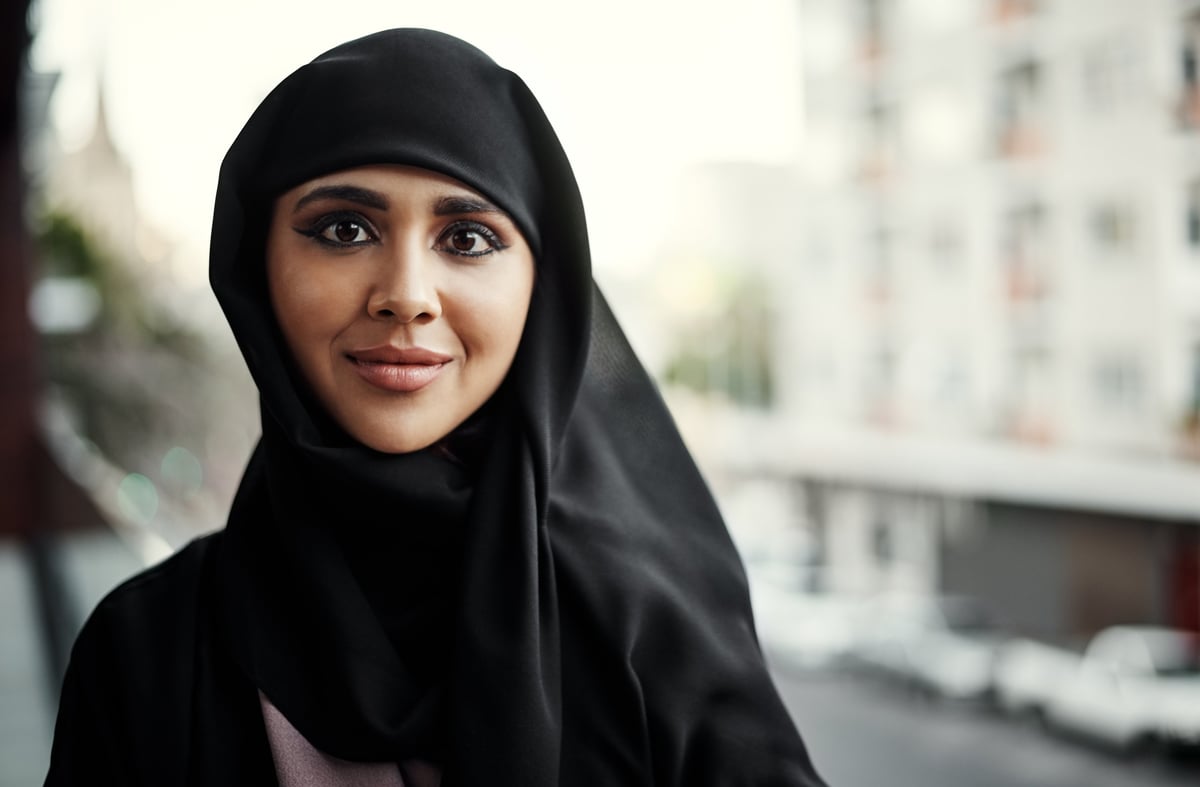 A confident businesswoman in hijab standing on an office balcony